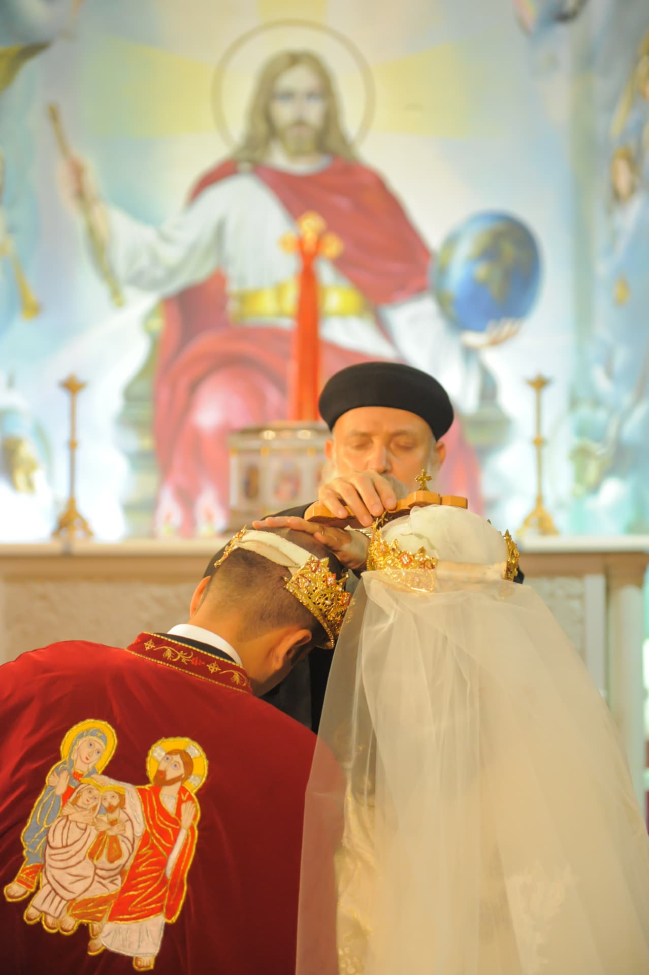 Priest crowning the bride and groom during a church ceremony