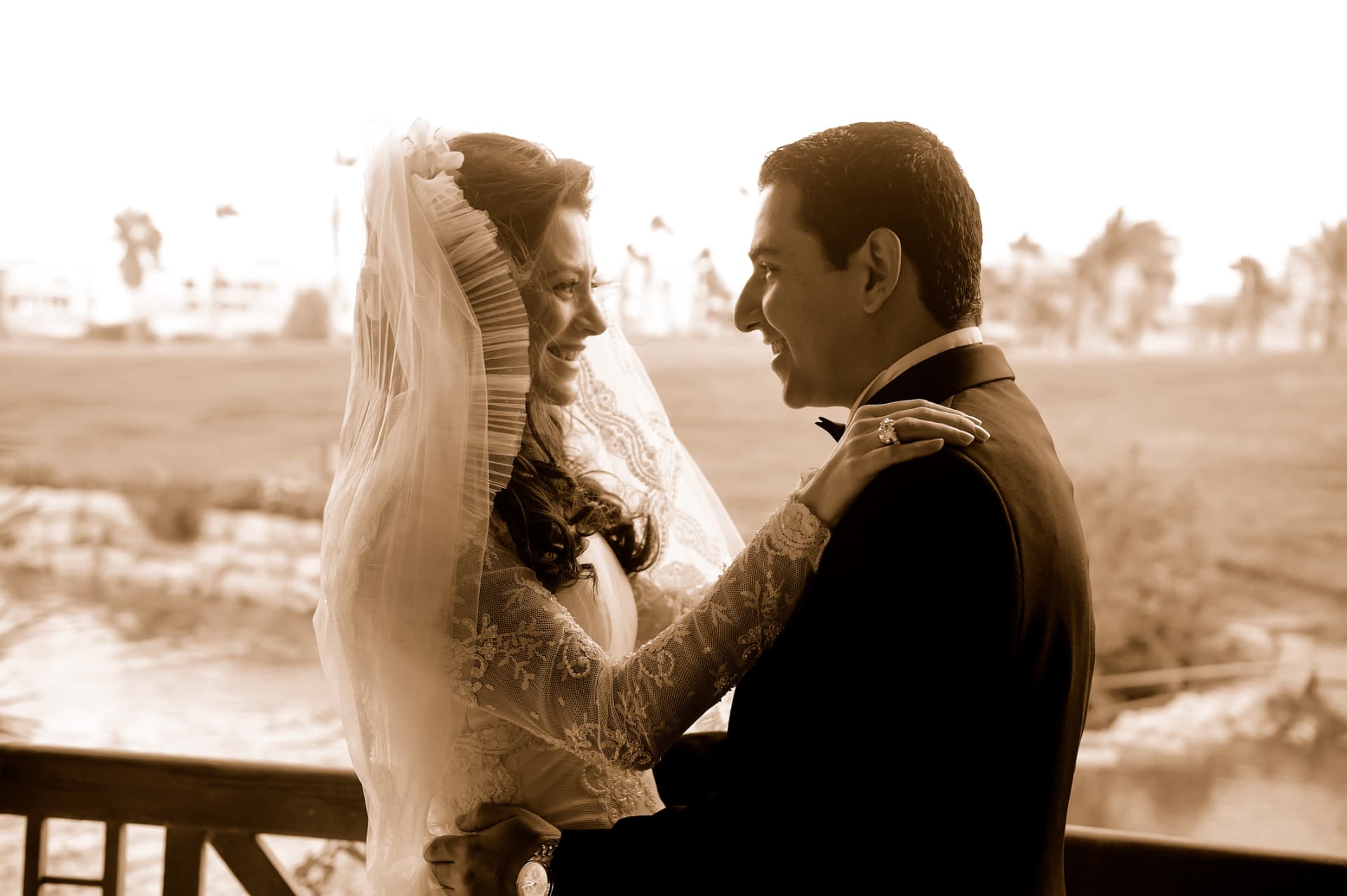 Bride and groom laughing together on a balcony