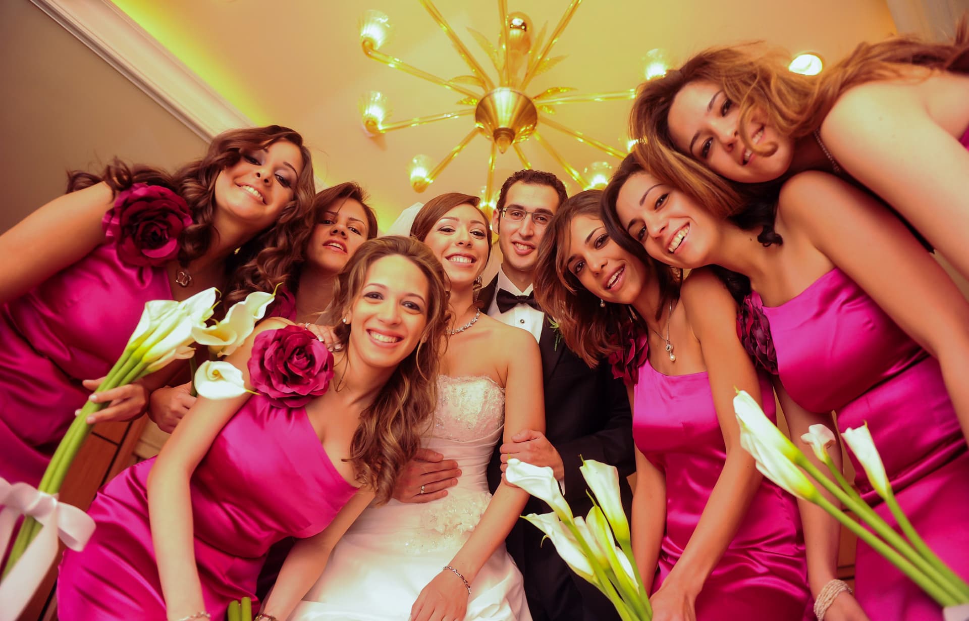 Bride surrounded by bridesmaids in pink holding calla lilies