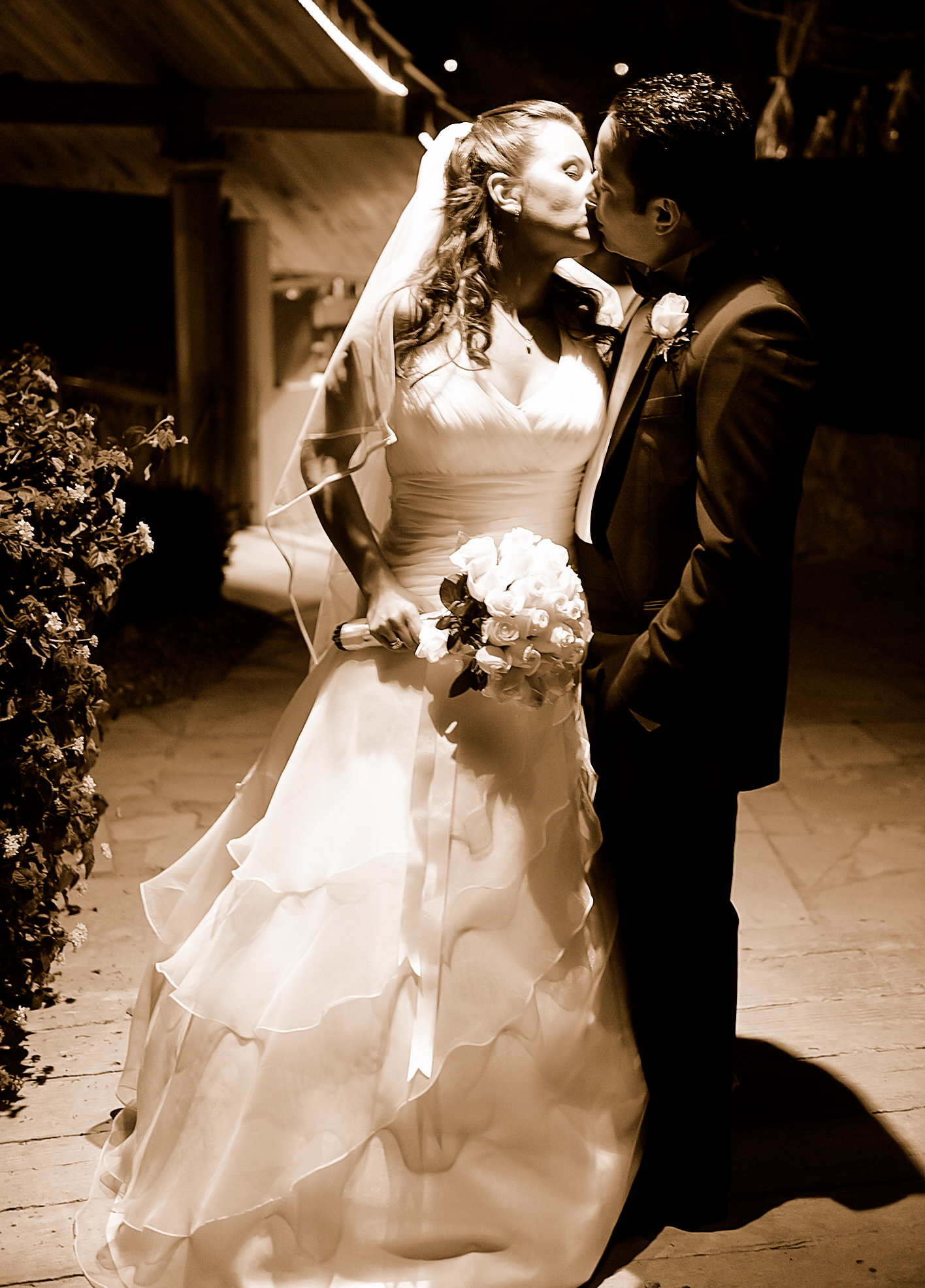 Sepia portrait of a couple kissing outdoors at night
