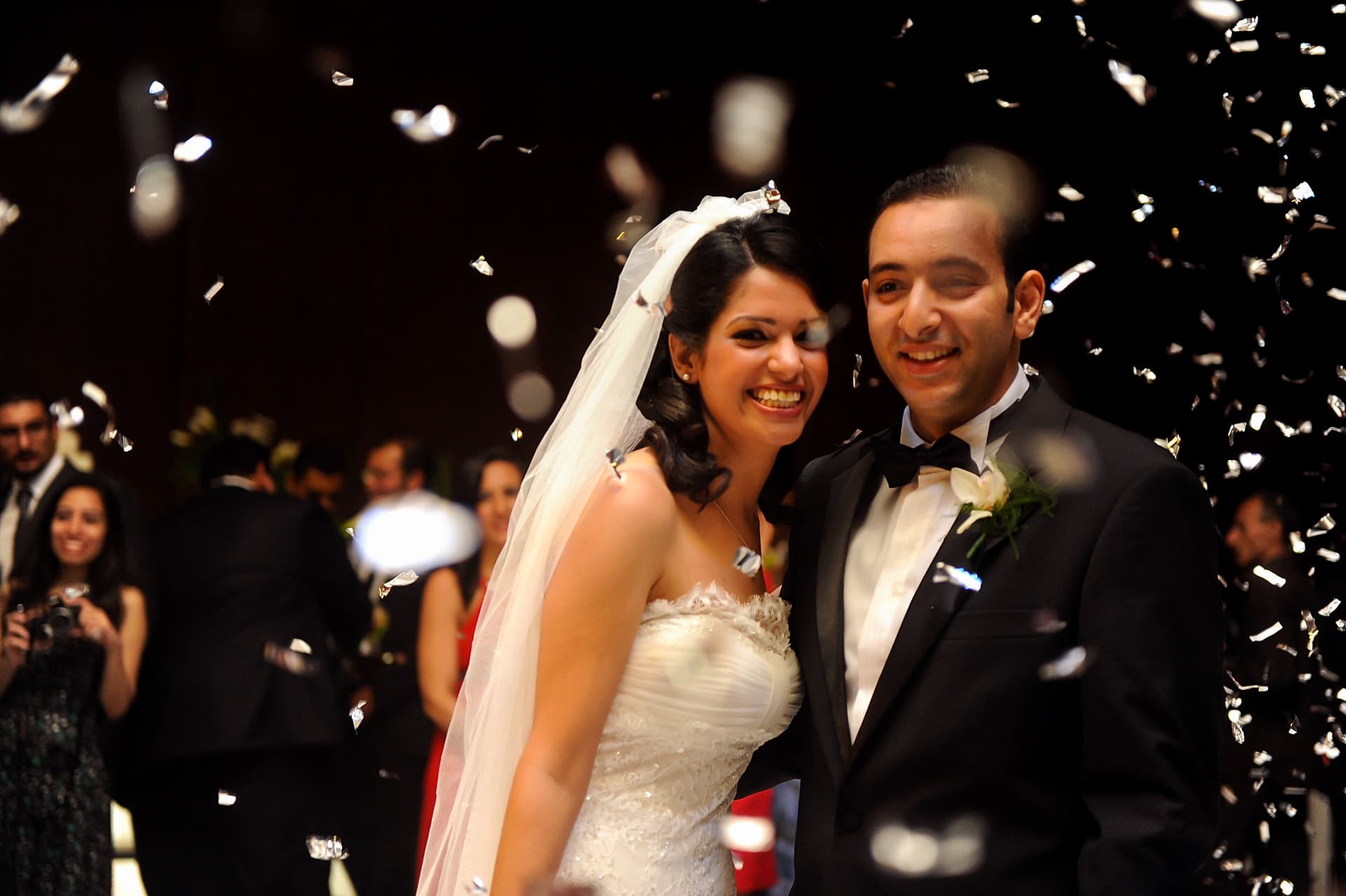 Couple beaming as silver confetti falls around them