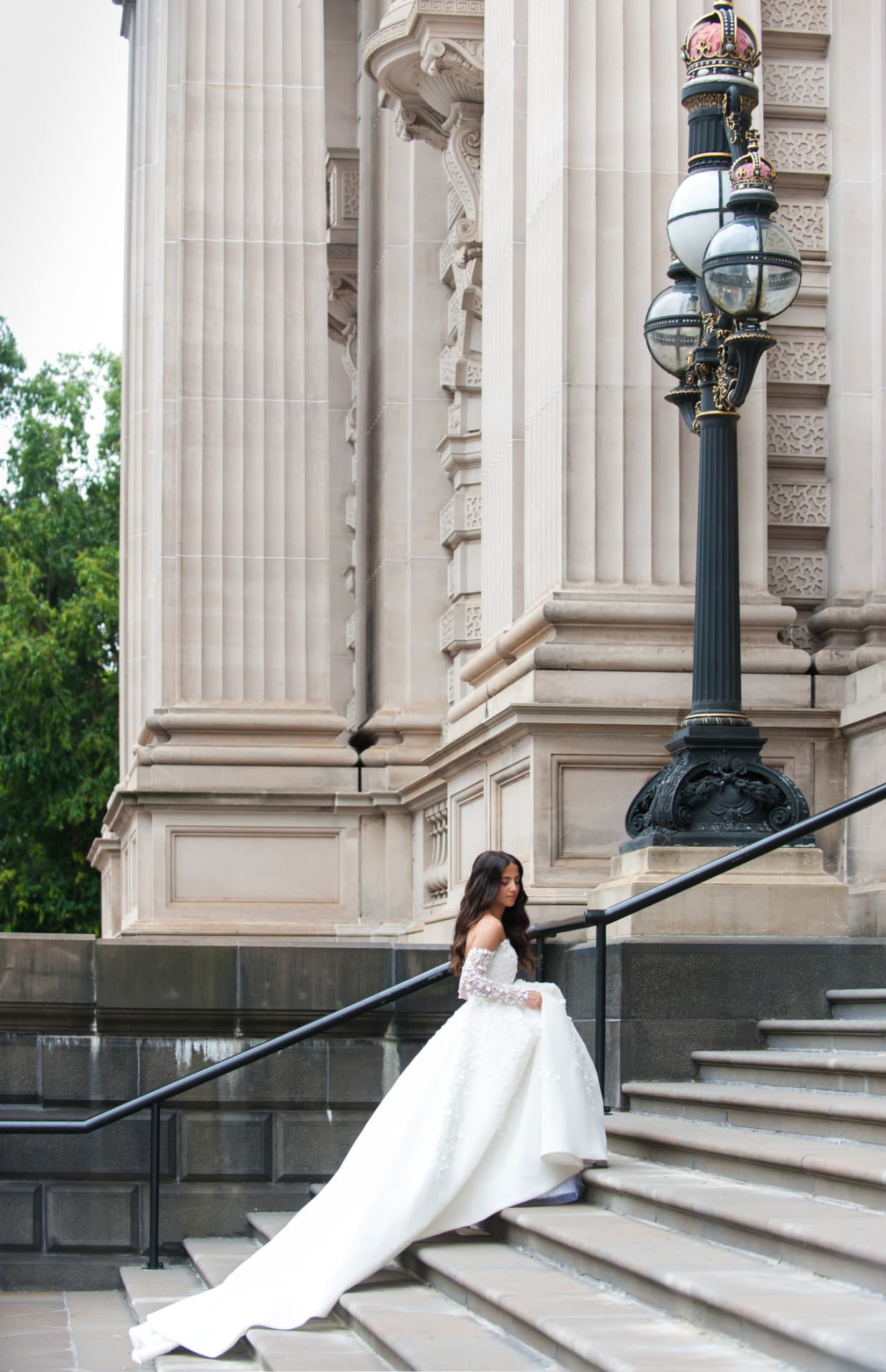 Bride on grand stone steps with her train flowing behind
