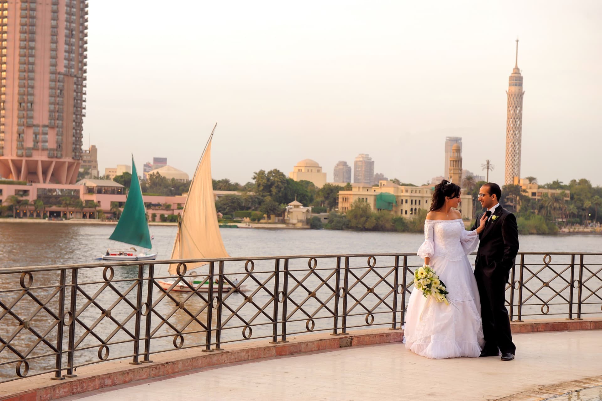 Bride and groom on a riverside promenade at golden hour
