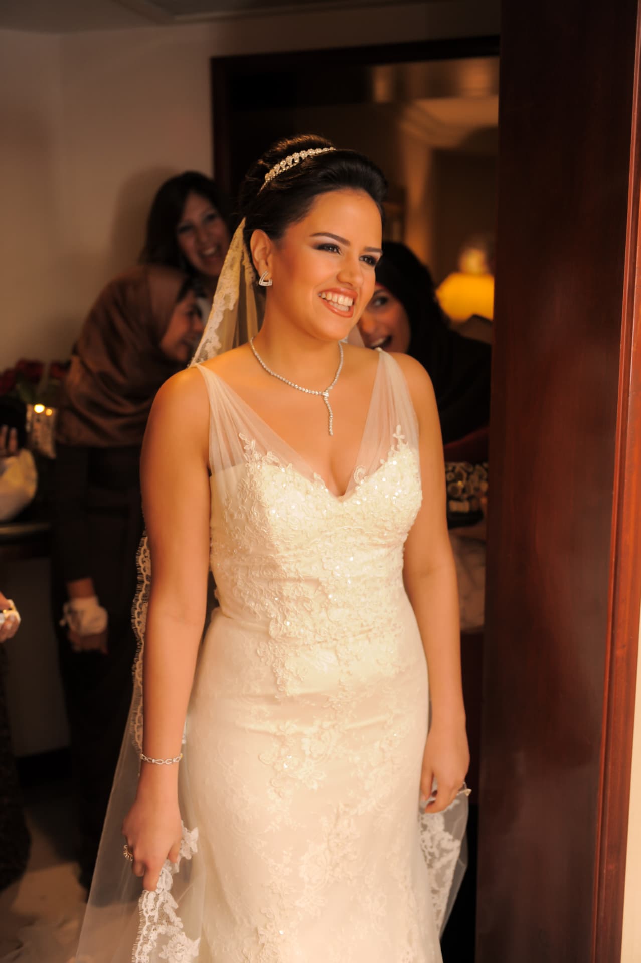Bride smiling in the doorway as family look on