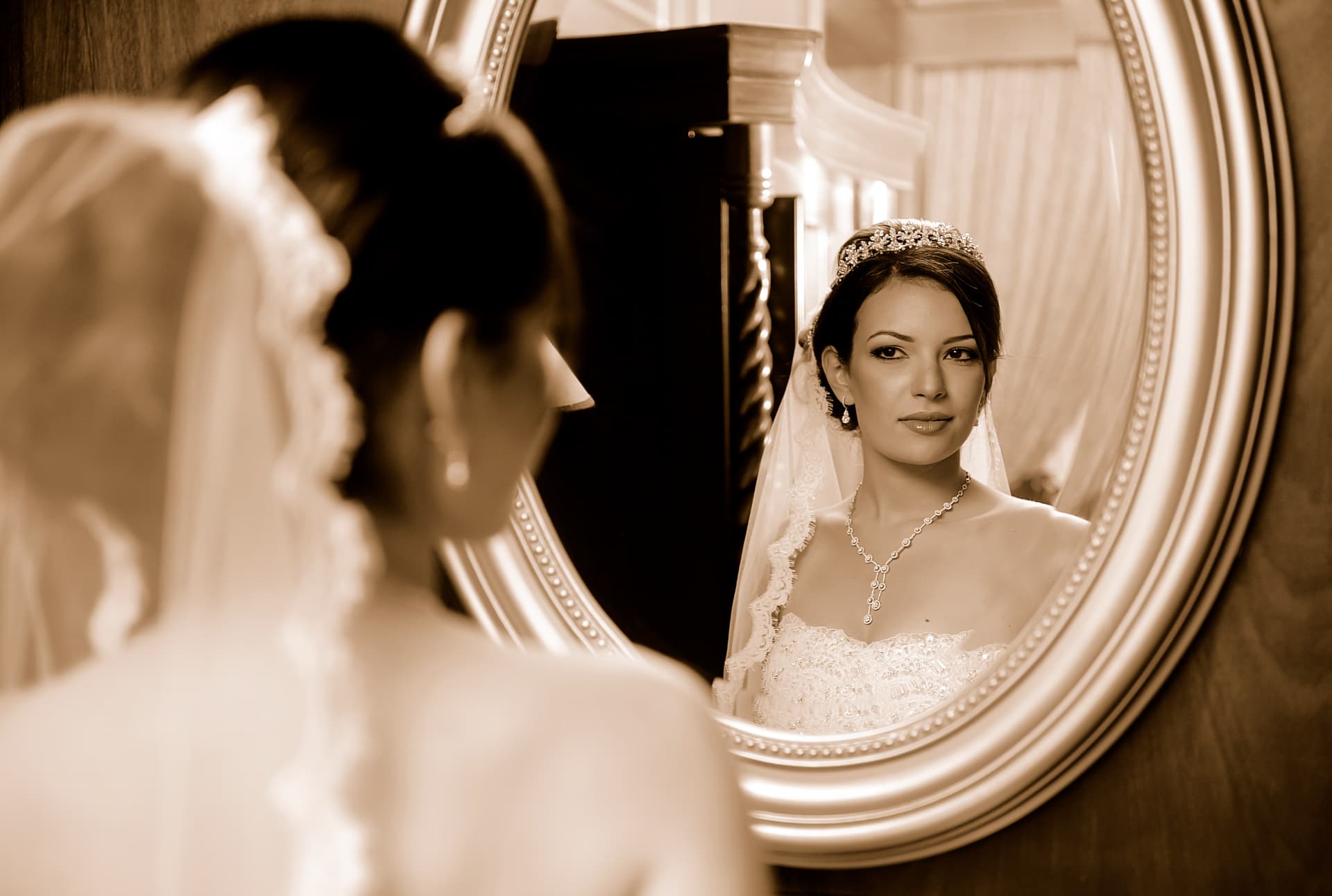Bride looking at her reflection in an oval mirror