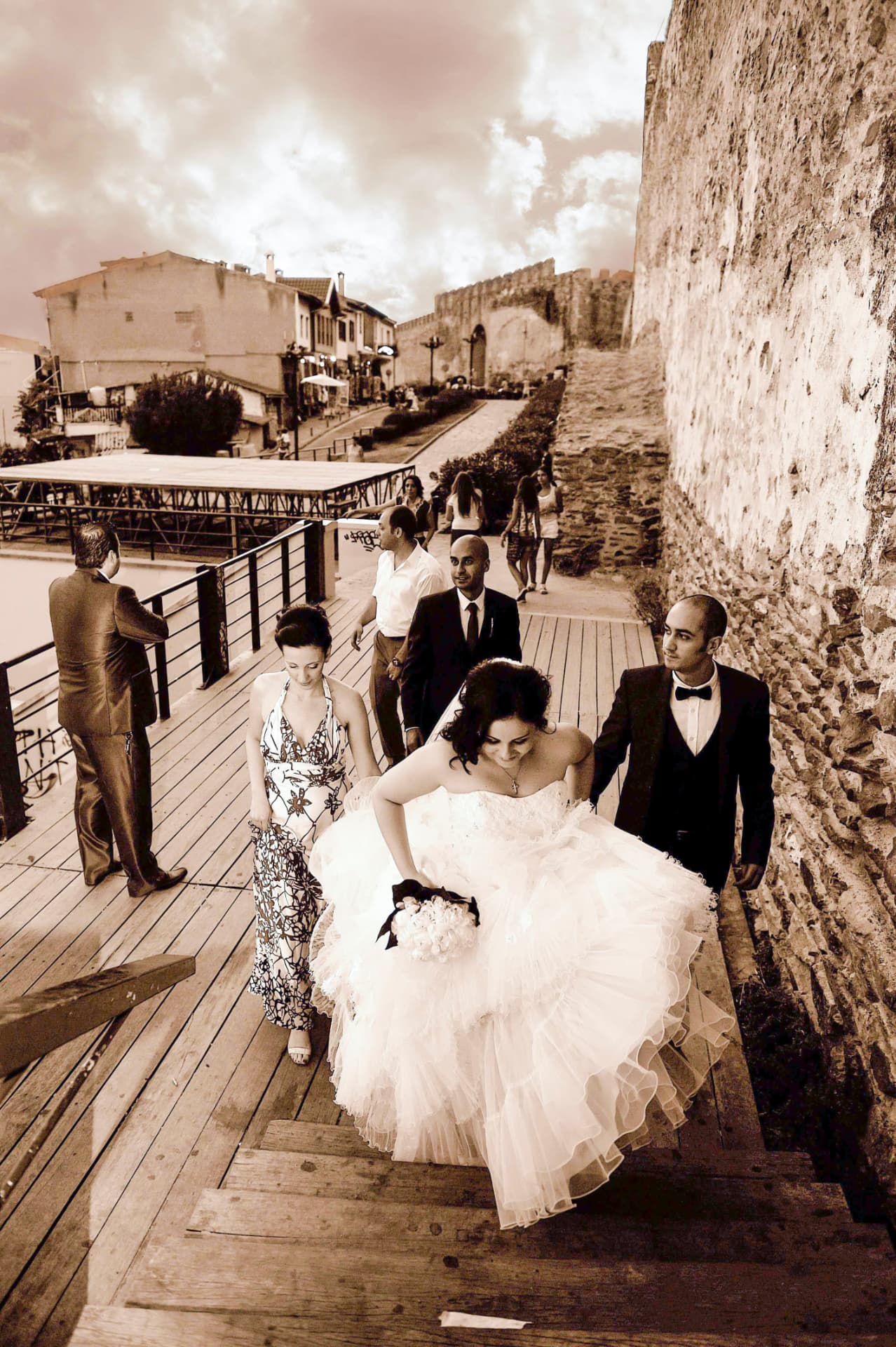 Wedding party climbing stone steps beside an old fortress wall