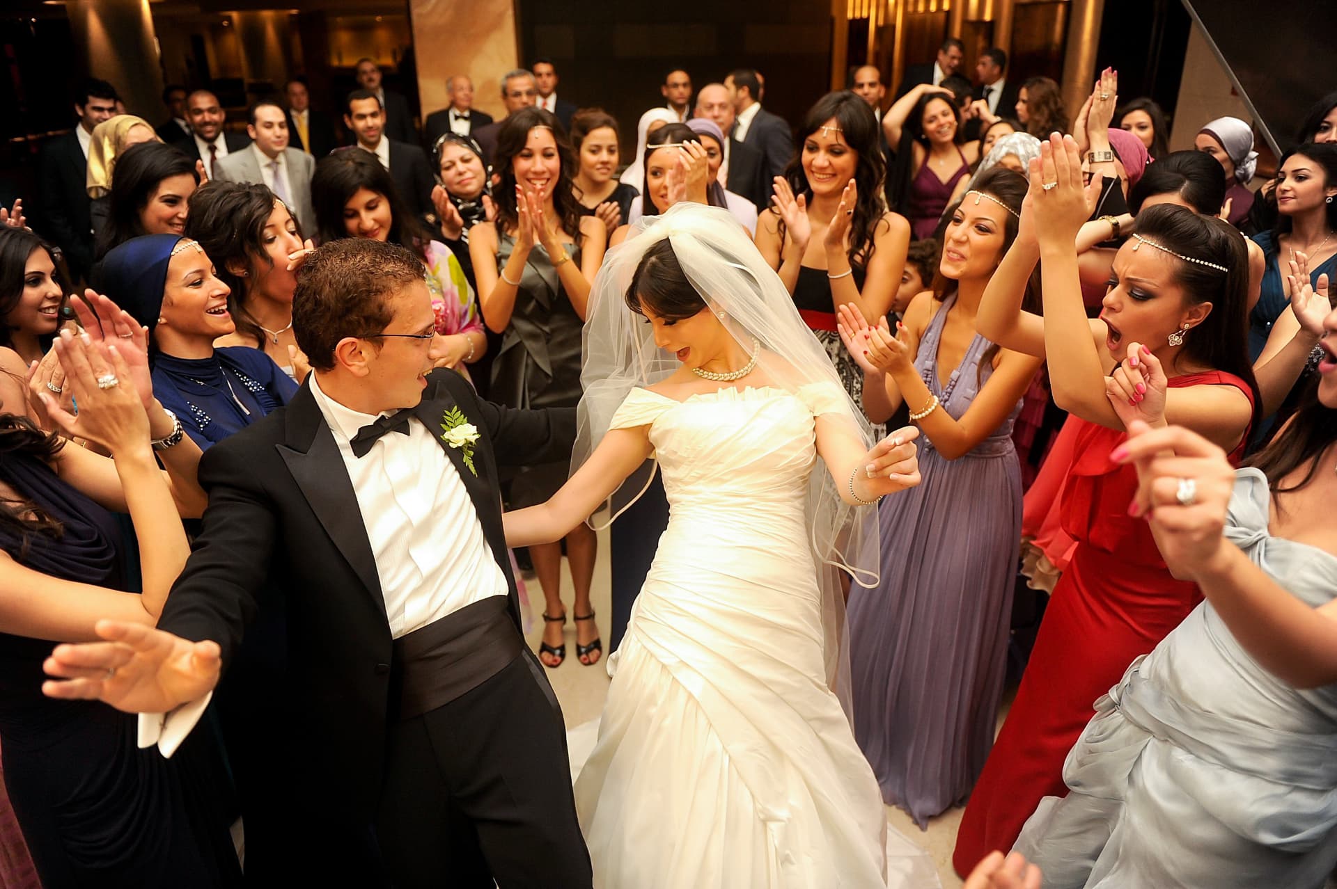 Bride and groom dancing surrounded by clapping guests