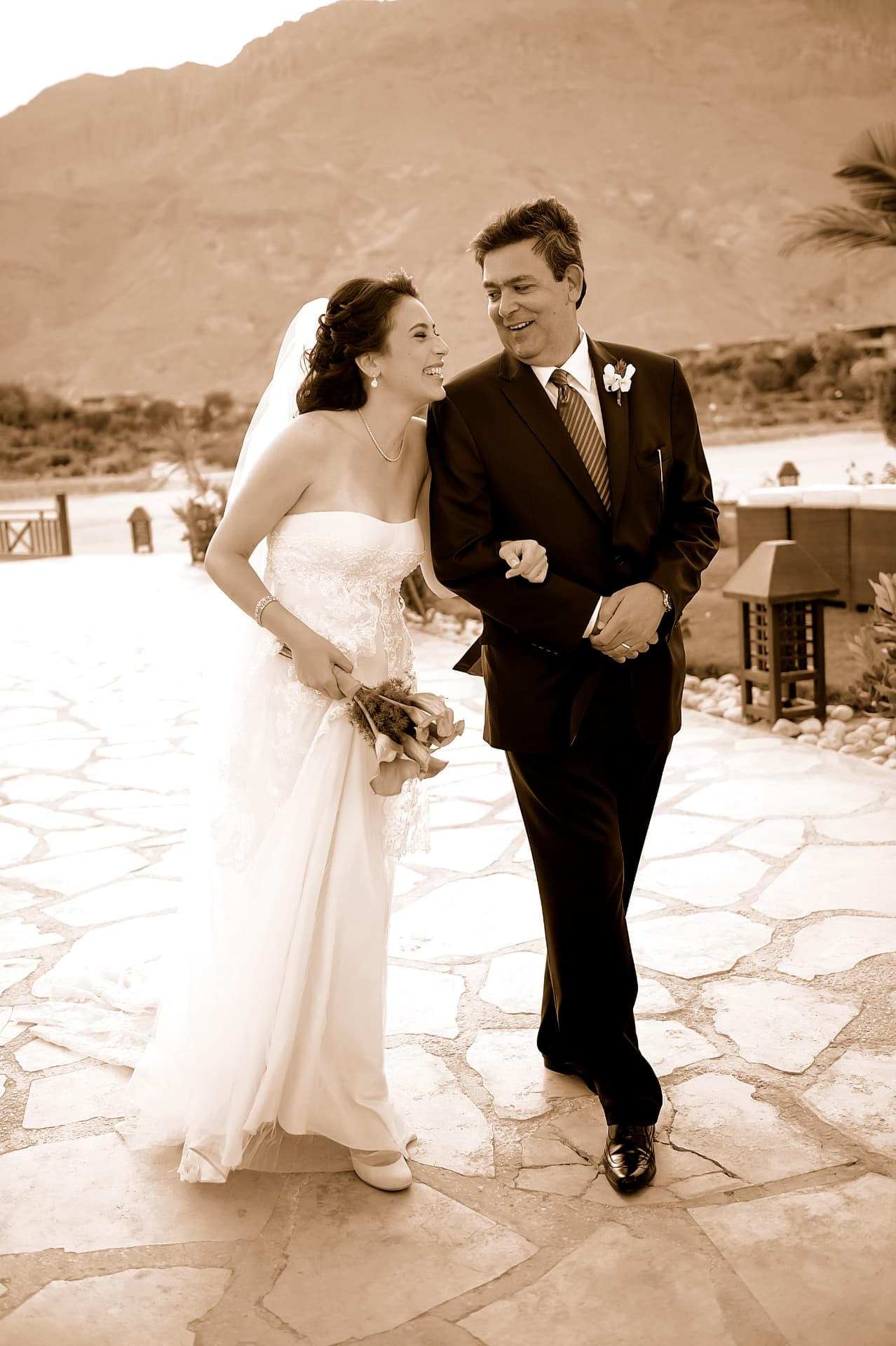 Bride laughing with the groom on a sunlit stone terrace