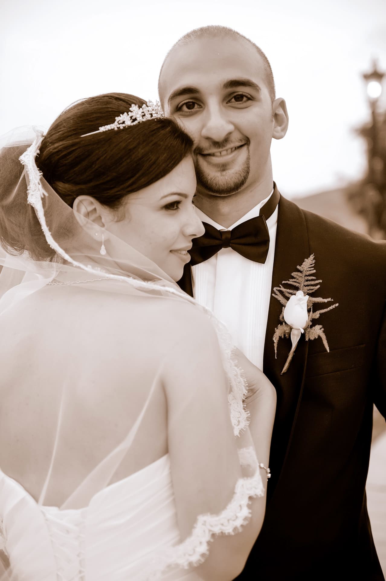 Bride in a tiara and veil resting against the smiling groom