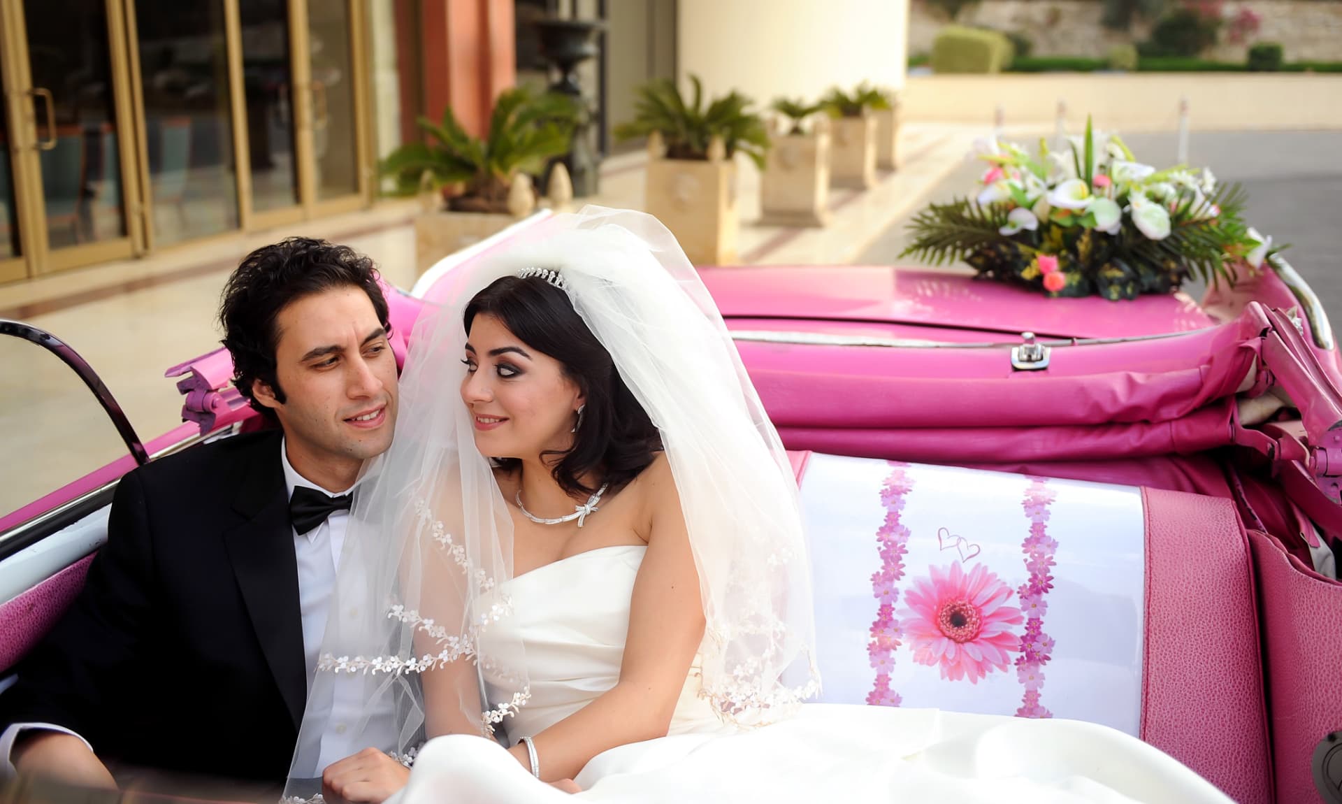 Couple seated in a vintage pink convertible