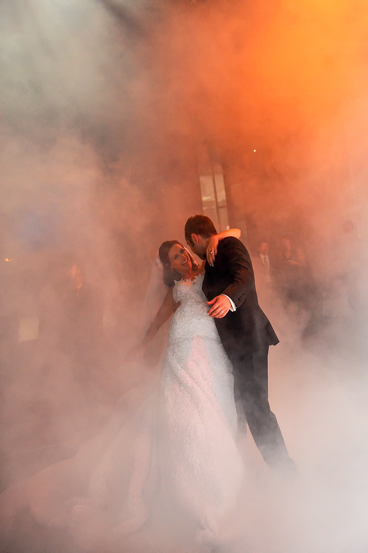 Couple dancing through orange-lit haze on the dance floor