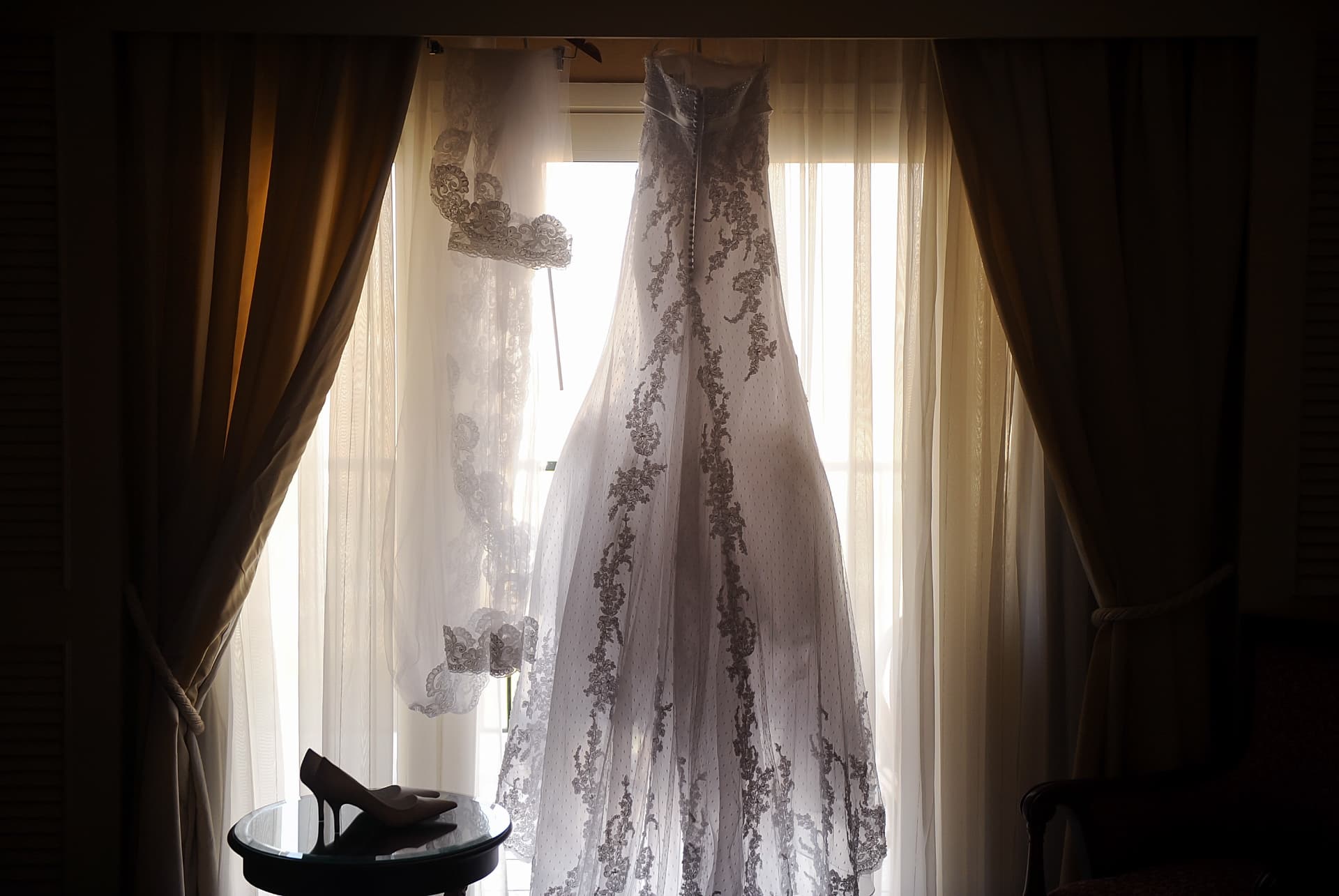 Wedding gown hanging in the window light
