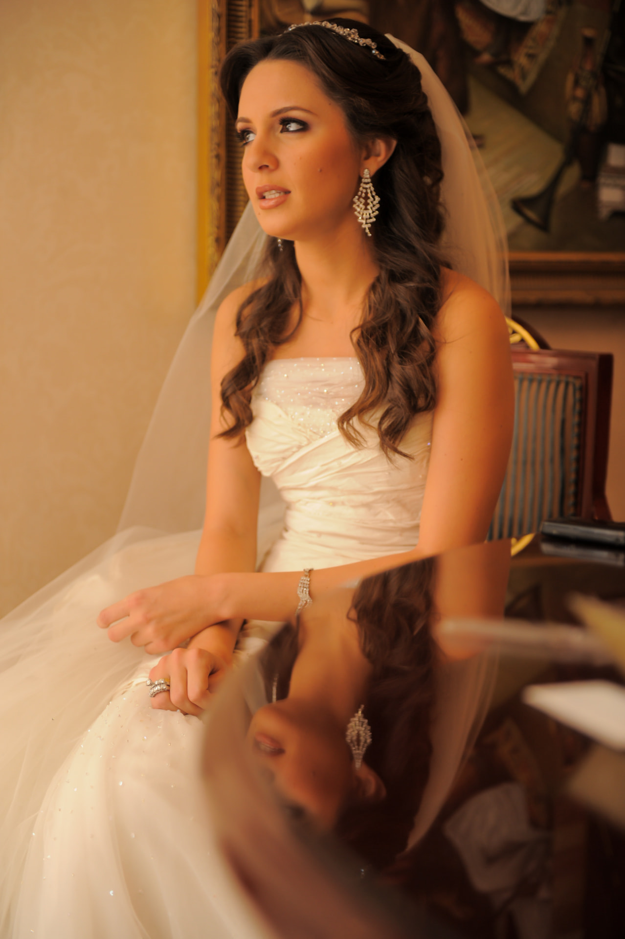 Seated bride in a veil and tiara gazing toward warm window light