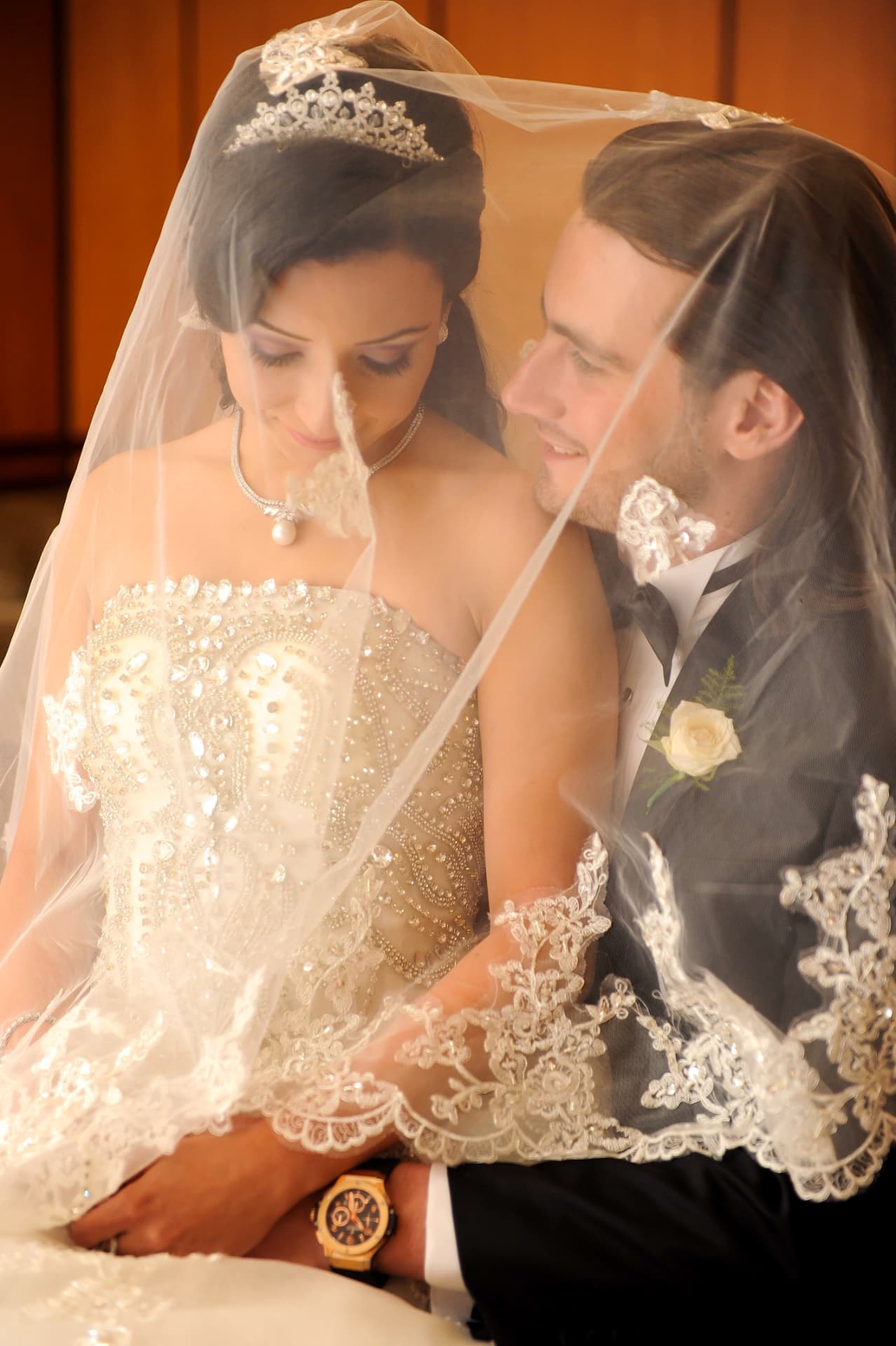 Bride and groom beneath her lace veil, sharing a quiet look