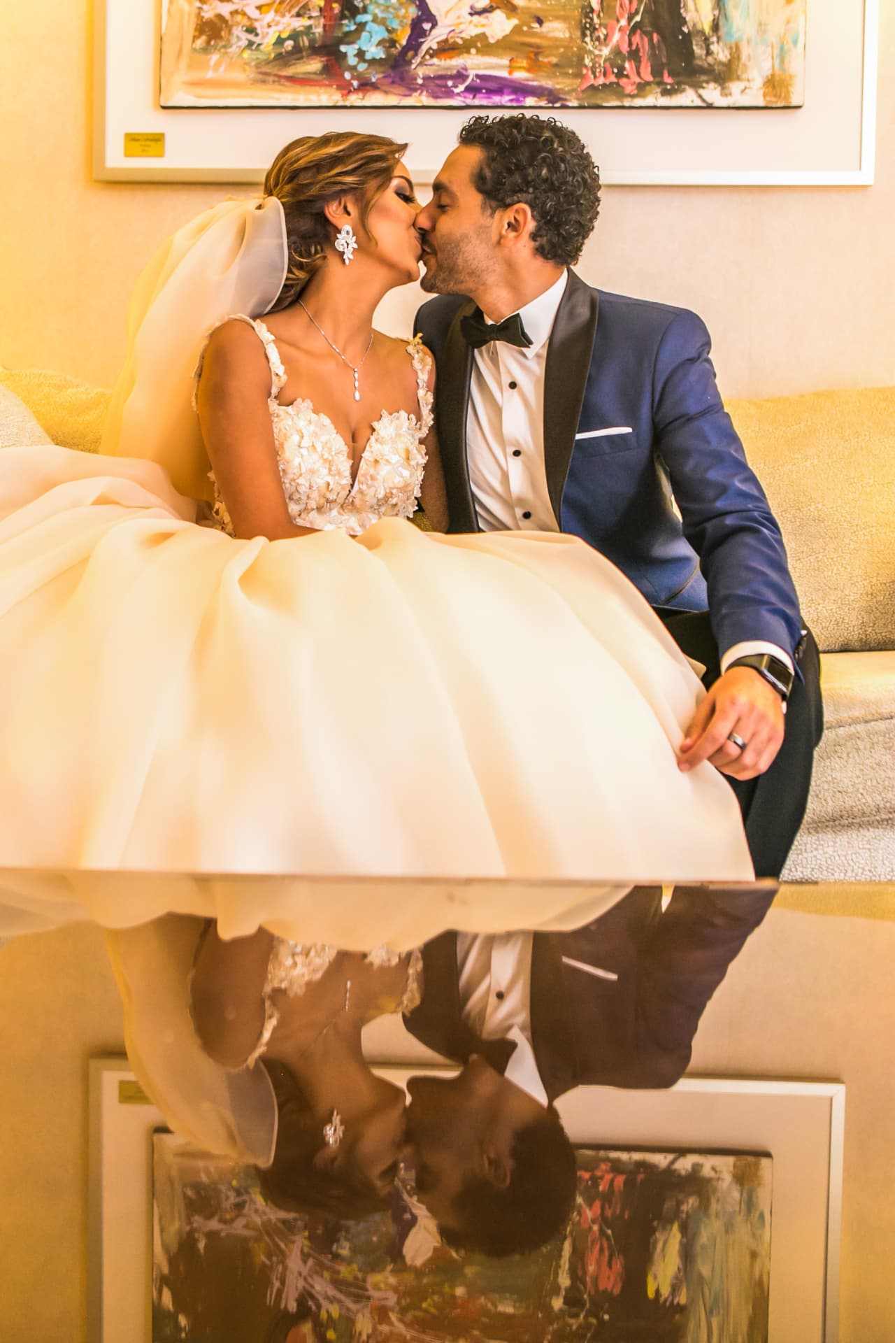 Couple kissing on a sofa with their reflection on a glass table