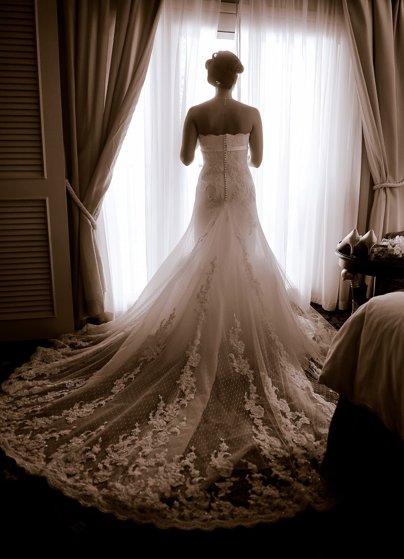 Bride at the window with her lace train spread behind her