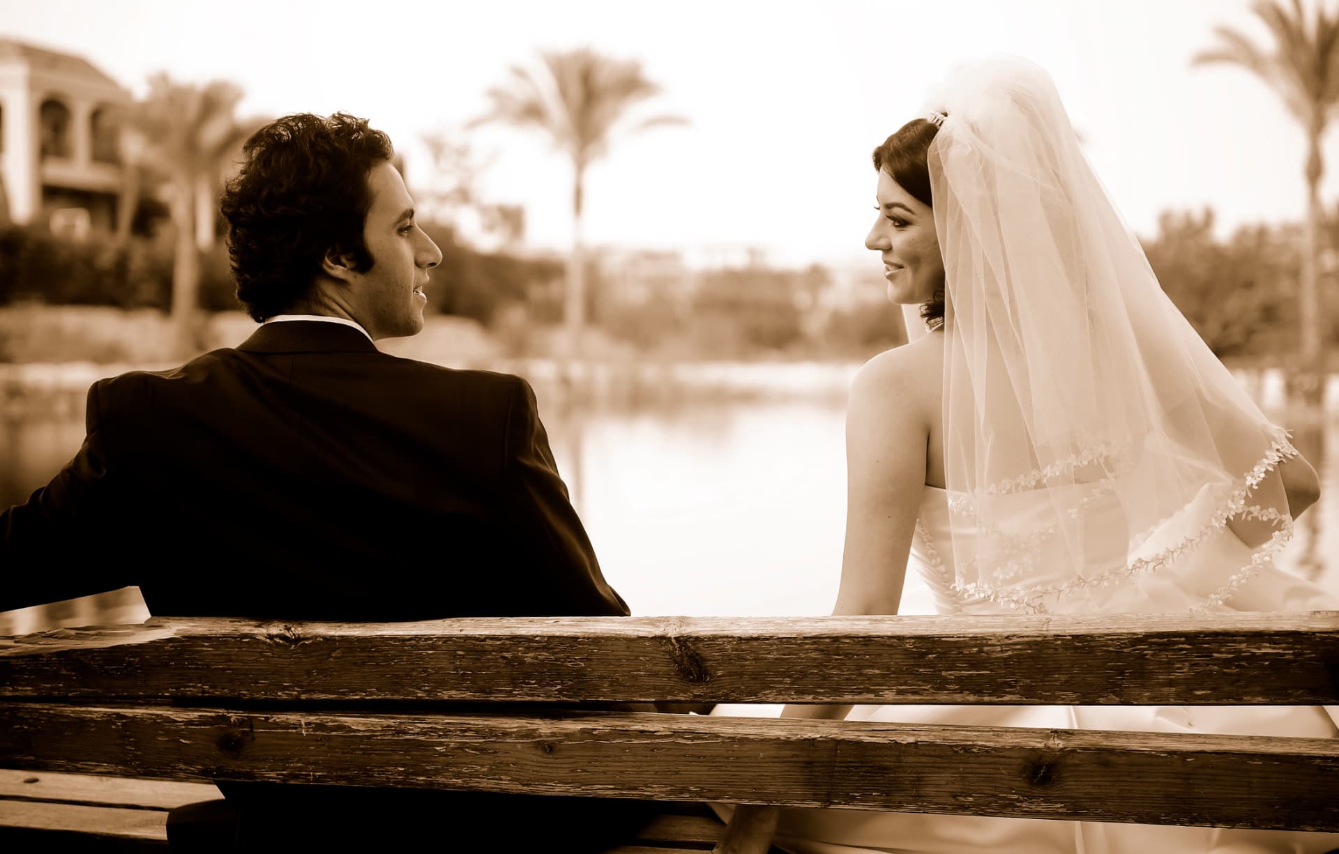 Couple on a lakeside bench looking at each other in sepia