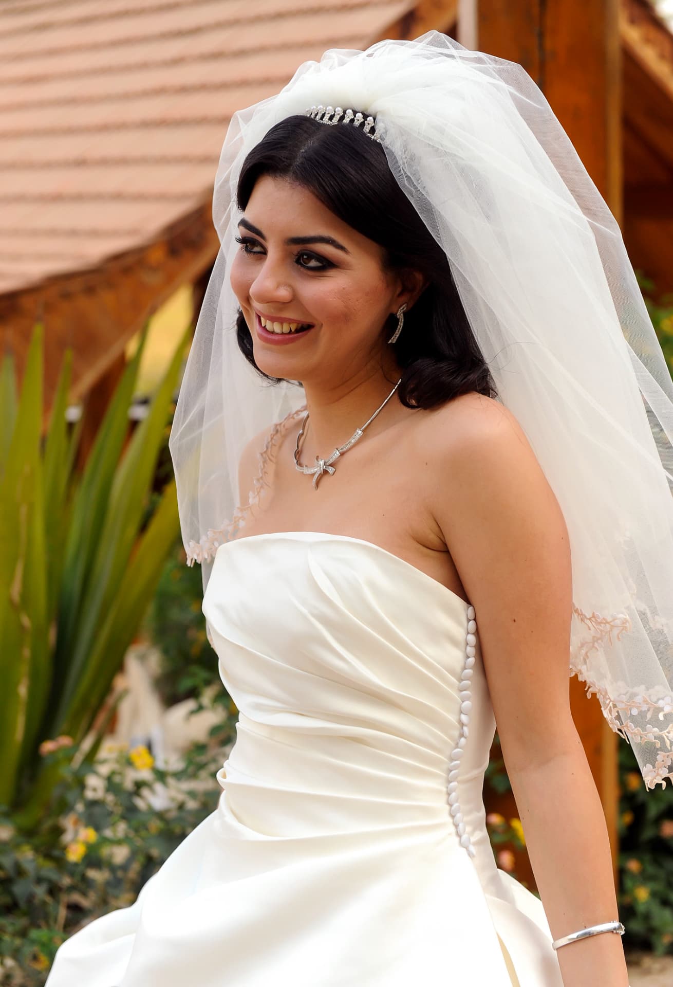 Bride smiling in the garden in a satin gown and veil