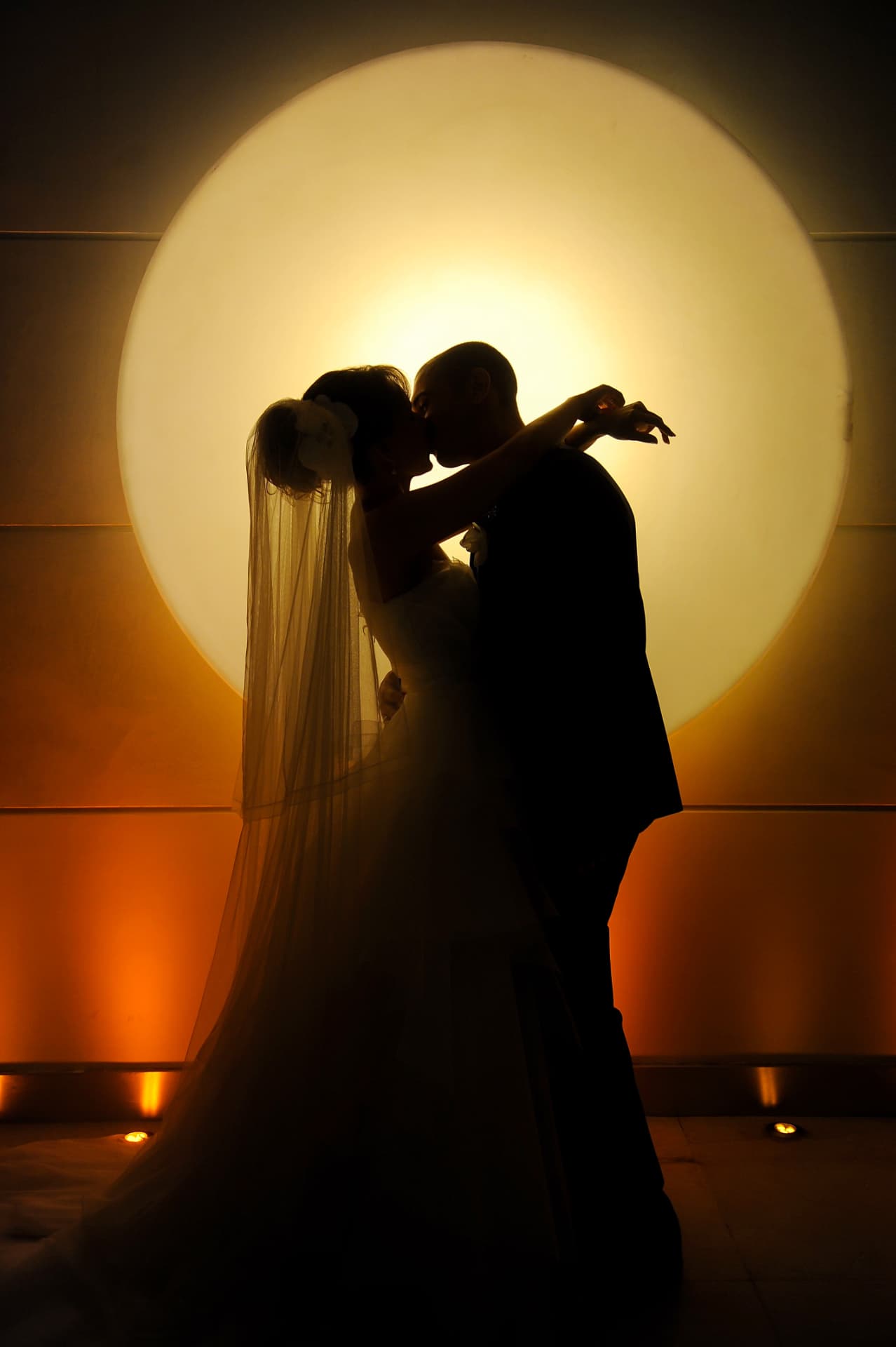 Silhouette of a couple kissing before a glowing circular light