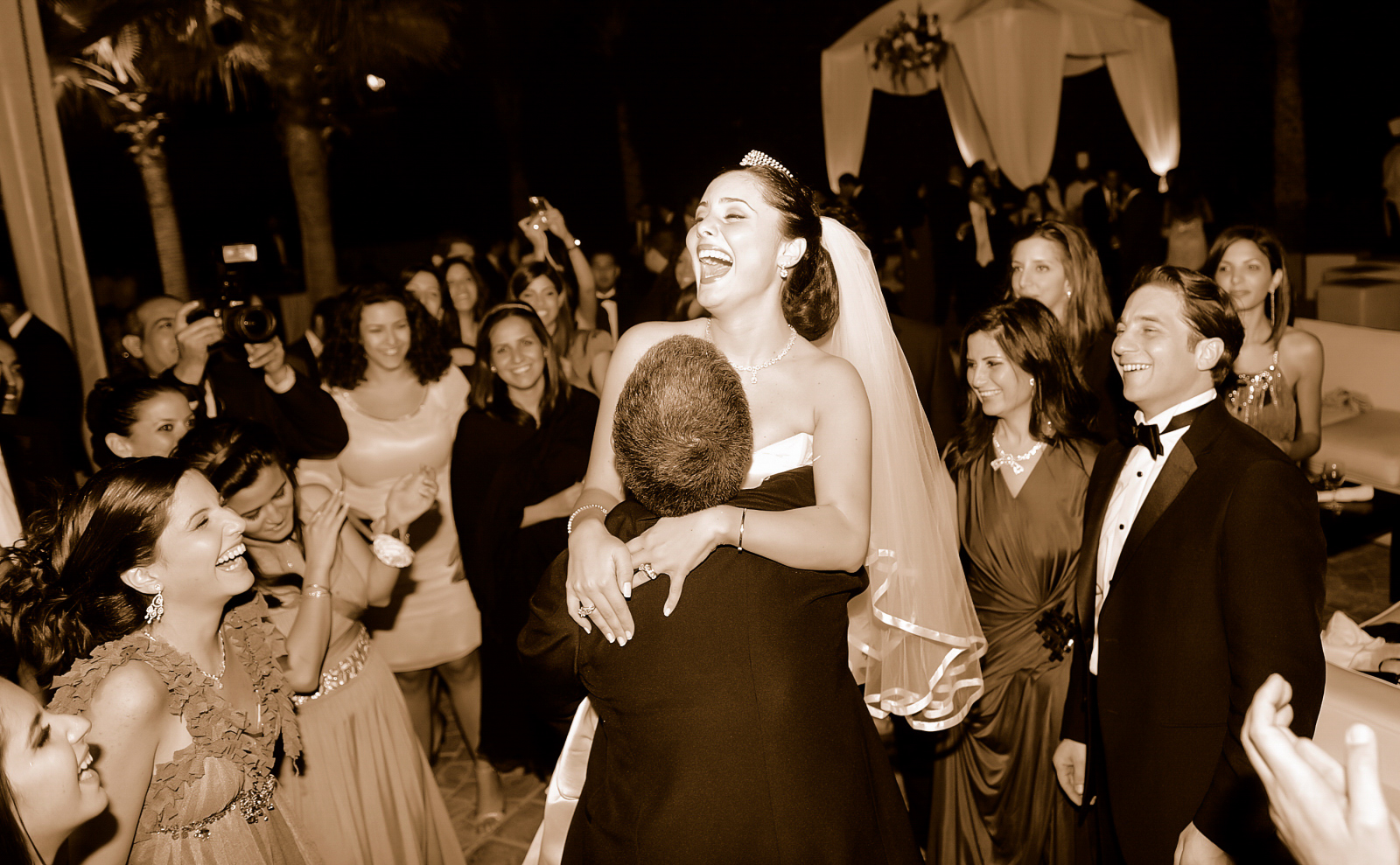 Bride laughing on the dance floor surrounded by guests