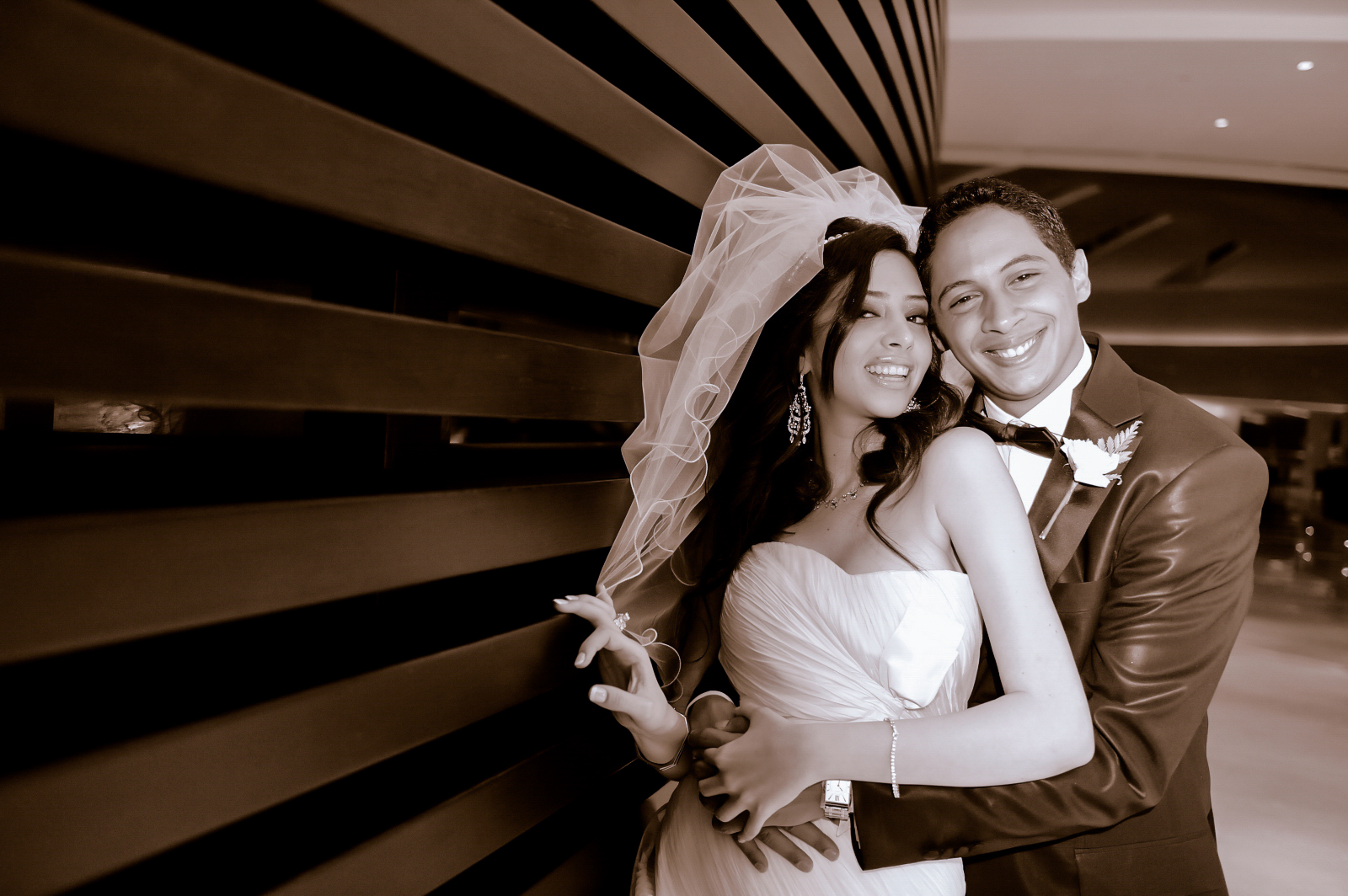 Bride and groom smiling cheek to cheek against a striped wall