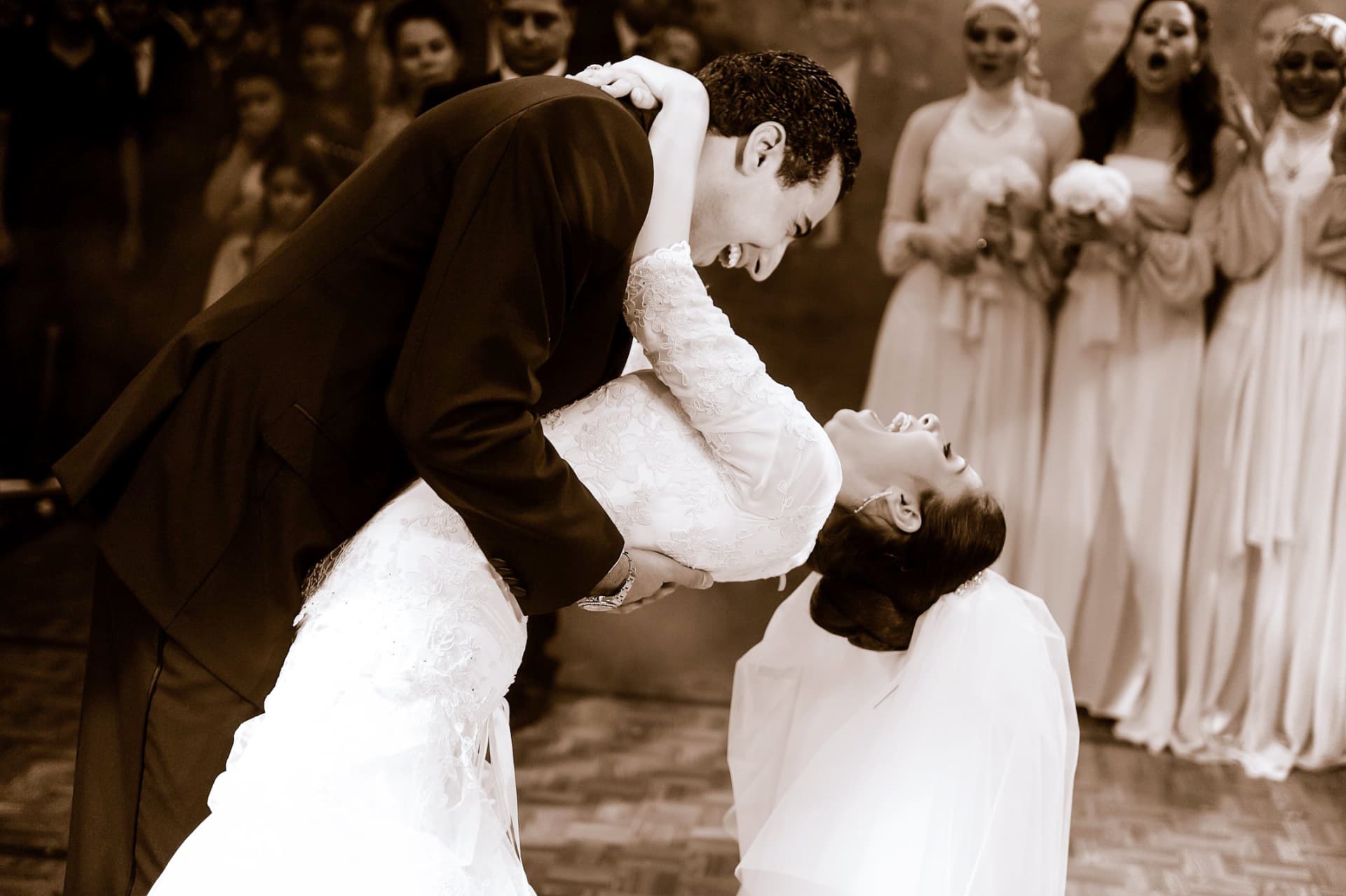 Sepia photograph of a groom dipping his bride during the first dance