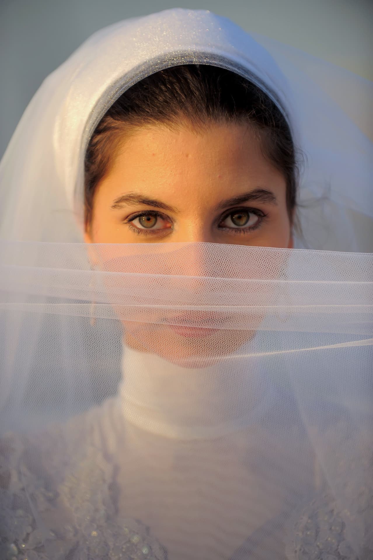 Close portrait of a bride behind her veil at golden hour