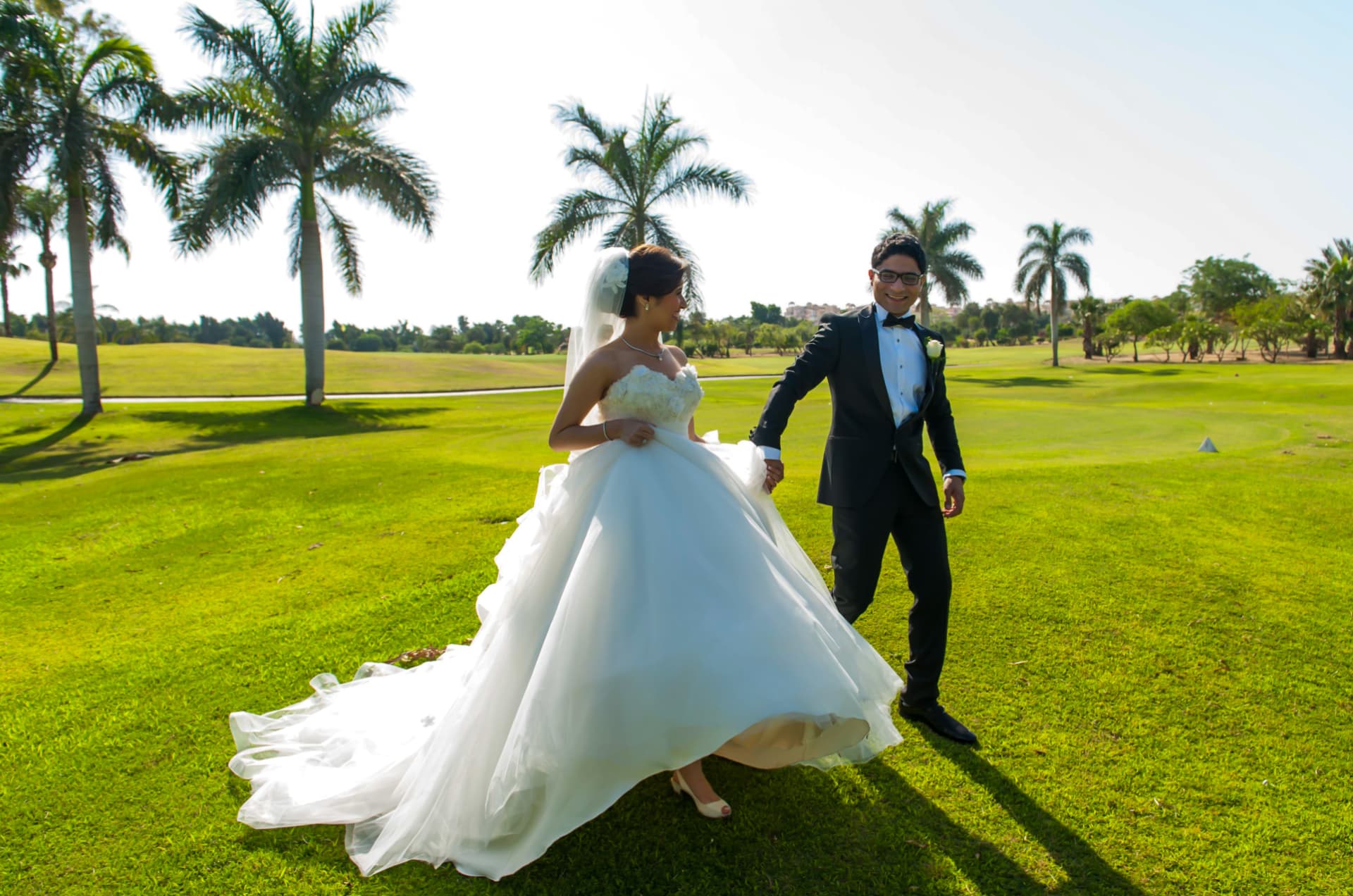 Bride twirling her gown on a sunlit lawn with the groom