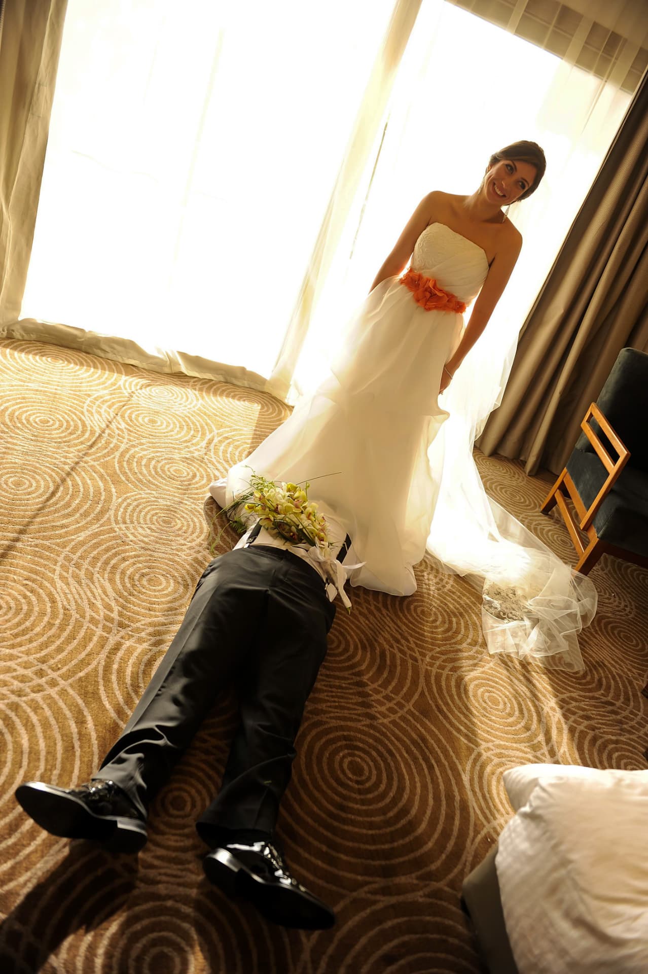 Playful photo of the groom lying at the bride's feet