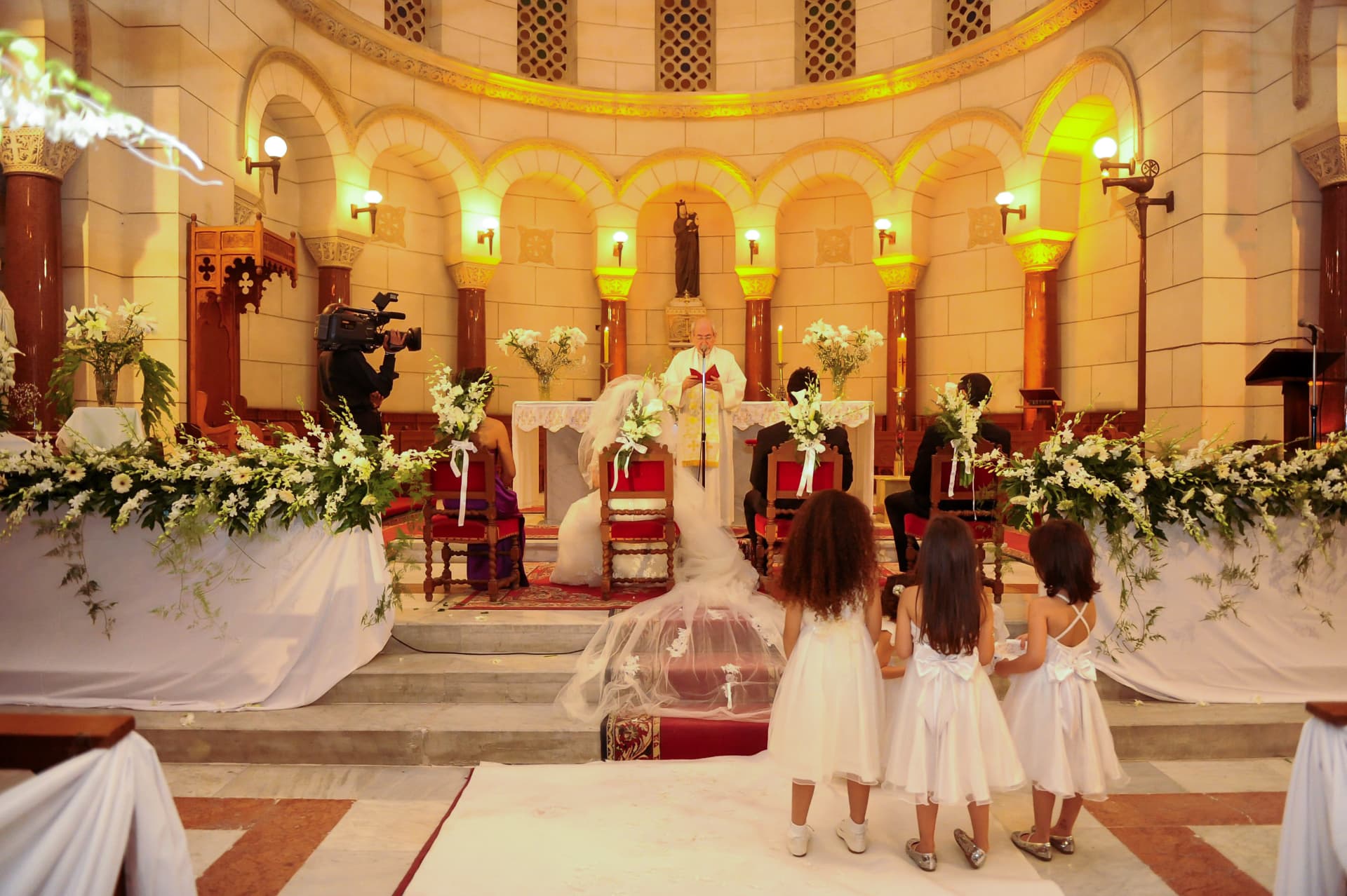 Church ceremony with flower girls watching the bride and groom at the altar